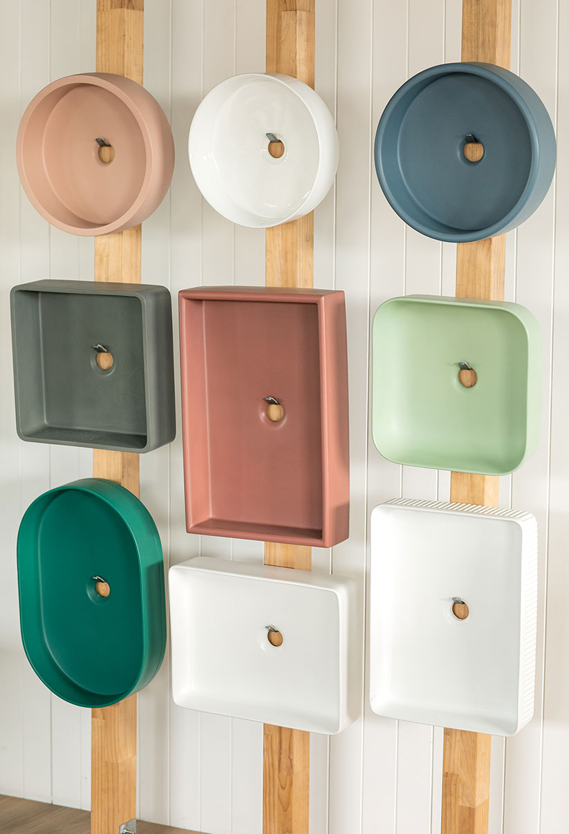 Multiple colourful bathroom basins displayed on a studio wall.